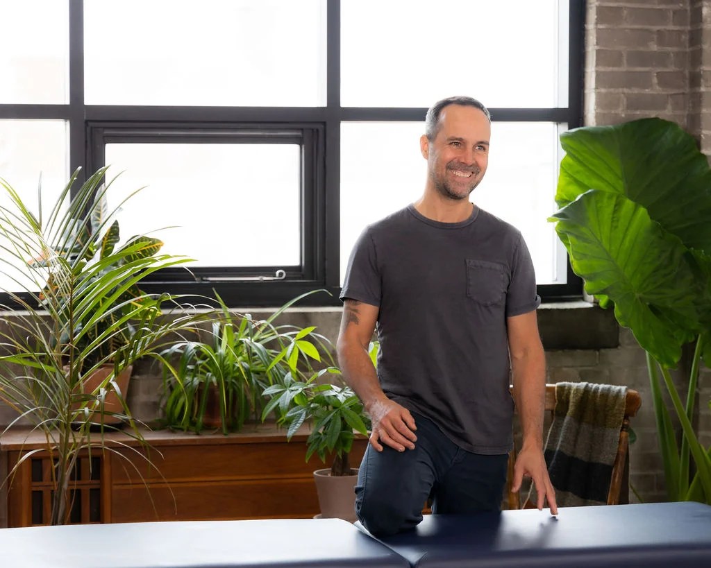 Ostéopathe souriant dans un espace de soin naturel et chaleureux